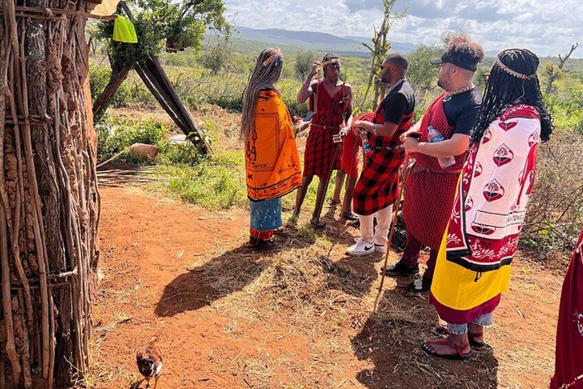 Un grupo de personas vestidas con atuendo tradicional de pie sobre un sendero de tierra, con un árbol y terreno rocoso al fondo. 2