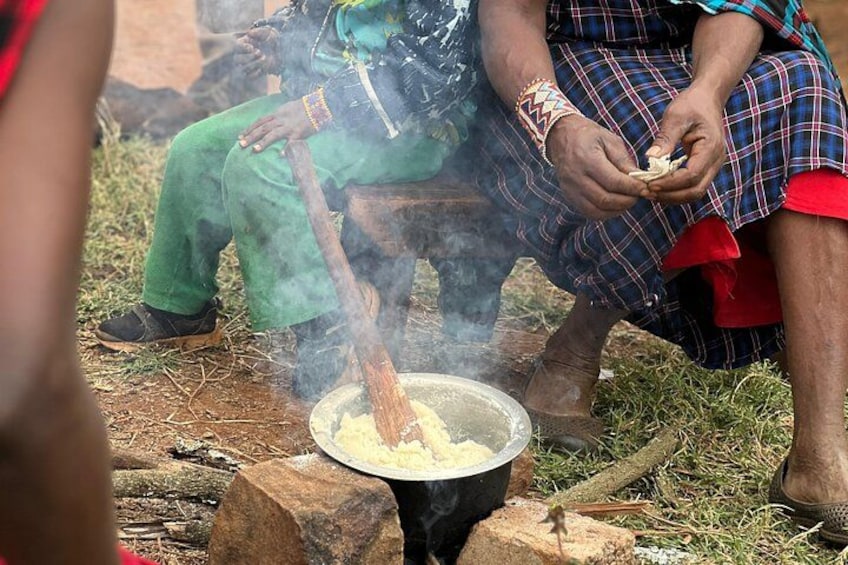 Menschen kochen draußen bei einem Topf auf einem Herd. 4