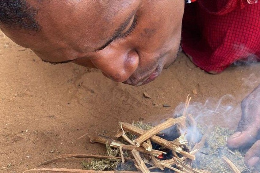Una persona cuidando una fogata, con leña y humo visibles. 3