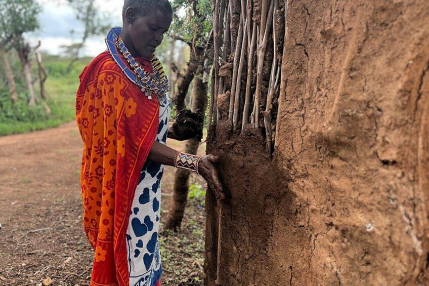 A person in traditional attire near a tree with a dirt ground. 4