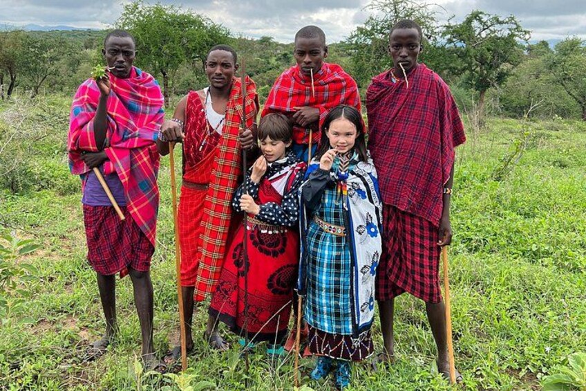 Un grupo de personas con vestimenta tradicional de pie en un campo con árboles al fondo. 5