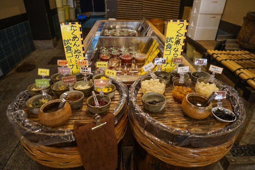 A food display with various condiments and sauces in glass containers, each labeled with text. 3