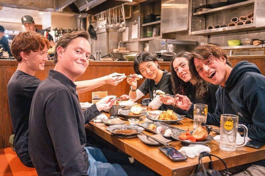 A group of people dining at a restaurant with various dishes on the table. 1