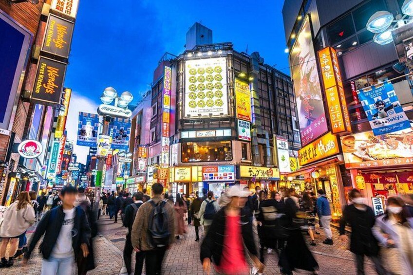 A bustling urban street at night with illuminated signs and billboards. 5