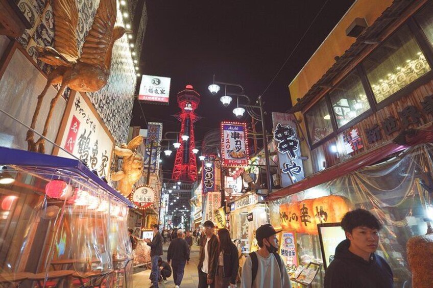 Una calle animada de noche con letreros iluminados y arquitectura tradicional. 4