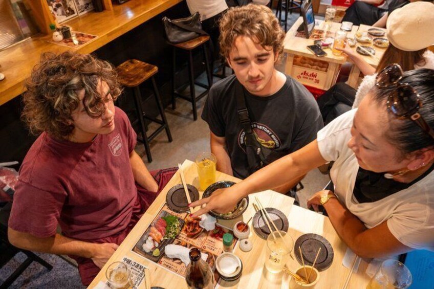 En gruppe mennesker spiser på en restaurant med mange forskellige retter og drikkevarer på bordet. 4