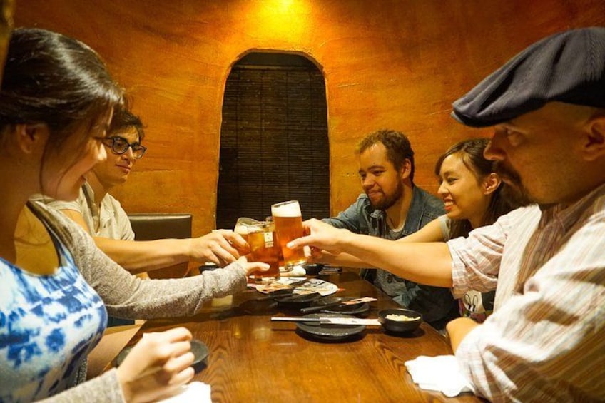 Un grupo de personas brindando con cerveza en una mesa de madera en una habitación cálidamente iluminada. 4