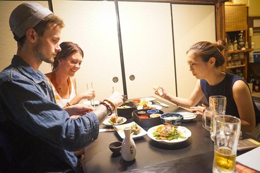 A group of people dining at a table with various dishes and drinks. 5