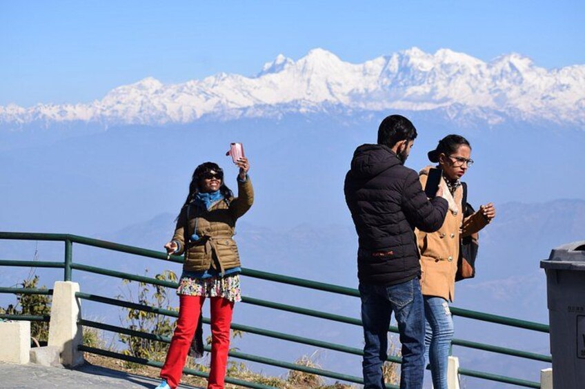 Three people standing on a railing with a mountainous landscape in the background. 3