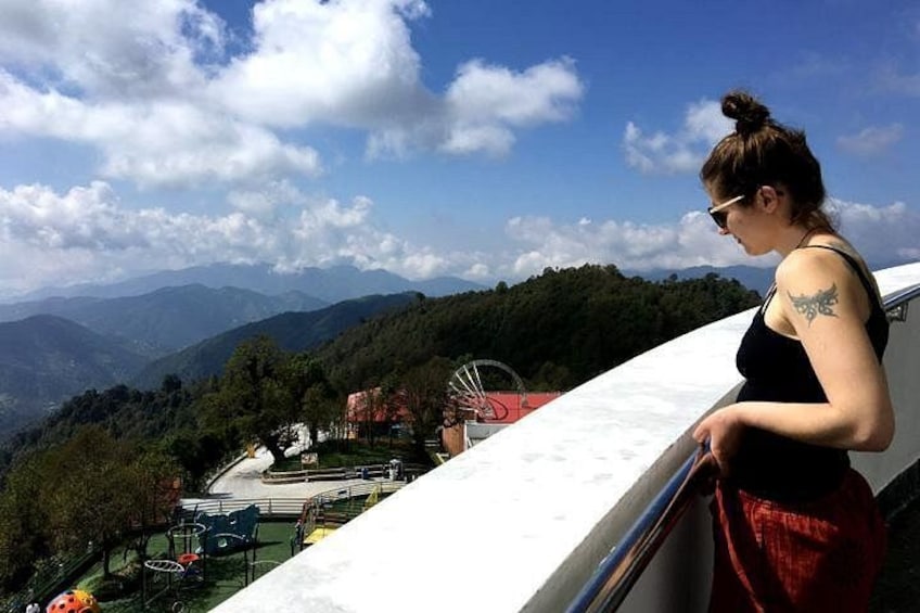 A person overlooking a mountainous landscape with a playground below. 1