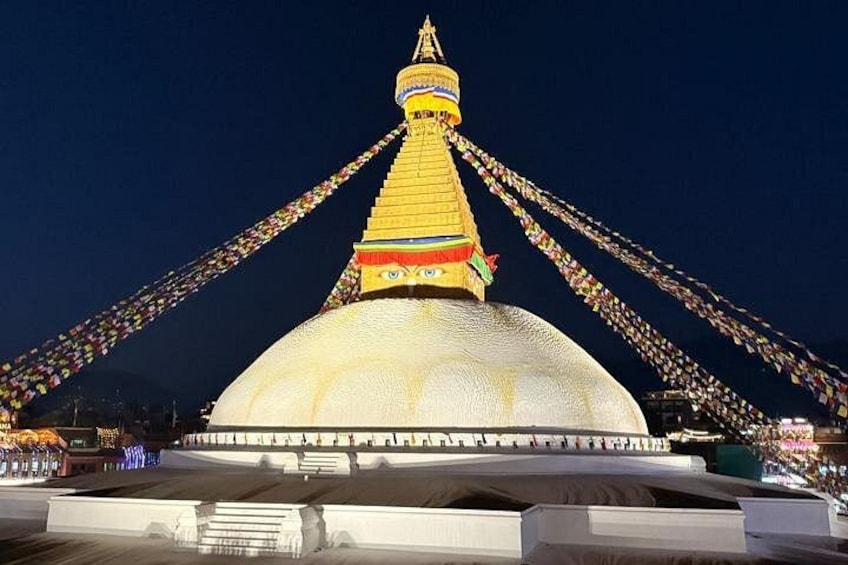 A large, white, domed structure with a golden spire, surrounded by colorful prayer flags. 1
