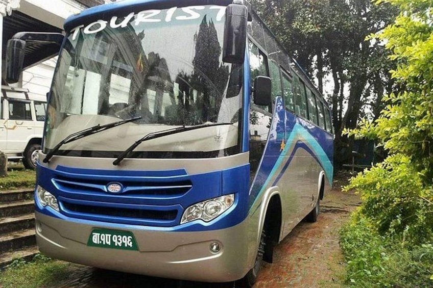 Ein blau-silberner Bus mit dem Schriftzug 'TOURIST' vorne, geparkt auf einem Feldweg, umgeben von Grün. 3