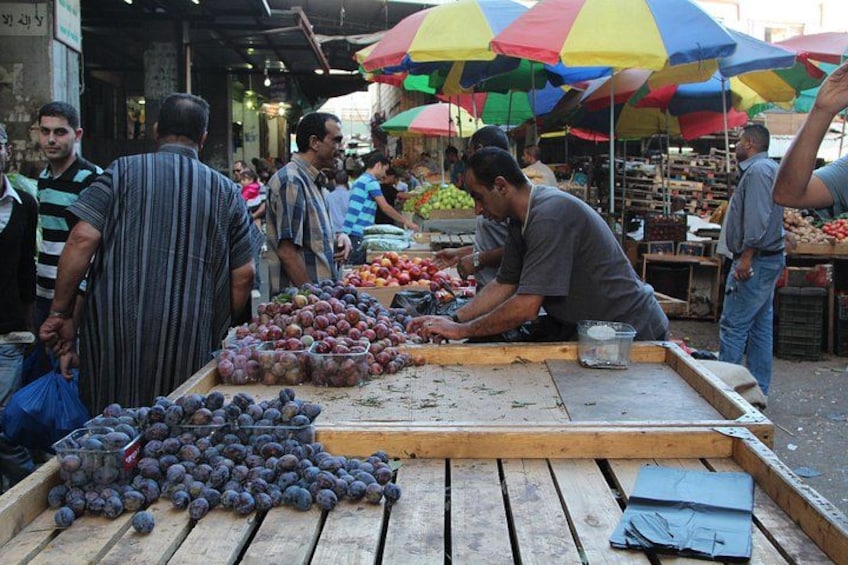 Un mercado de frutas con gente comprando y vendedores ofreciendo frutas. 5