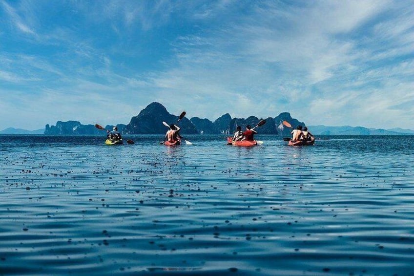 Quattro persone che fanno kayak su acqua calma, con montagne sullo sfondo. 4