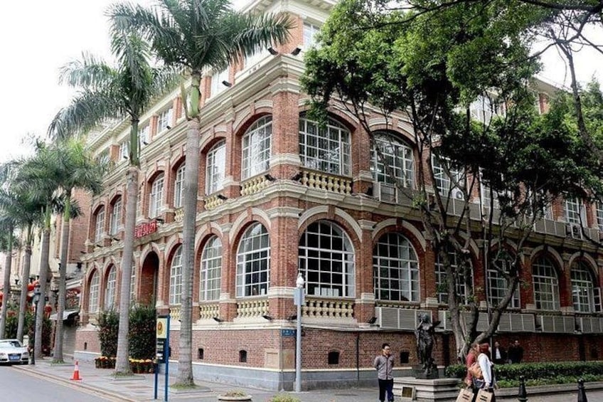 A historic building with arched windows and brick facade, surrounded by palm trees and pedestrians. 4