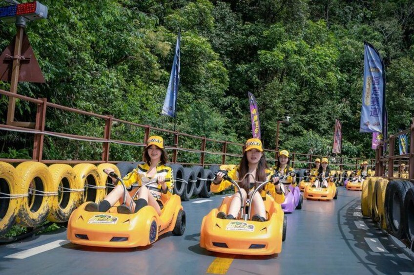 People in yellow go-karts on a track surrounded by greenery. 3