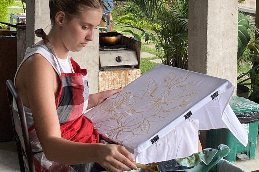 Una persona seduta all'aperto, che tiene in mano un oggetto bianco con decorazioni dorate, forse un mobile o un'attrezzatura. 2
