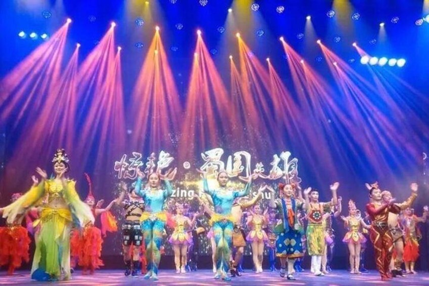Un grupo de artistas con vestuarios llamativos en un escenario con un fondo de luces. 1