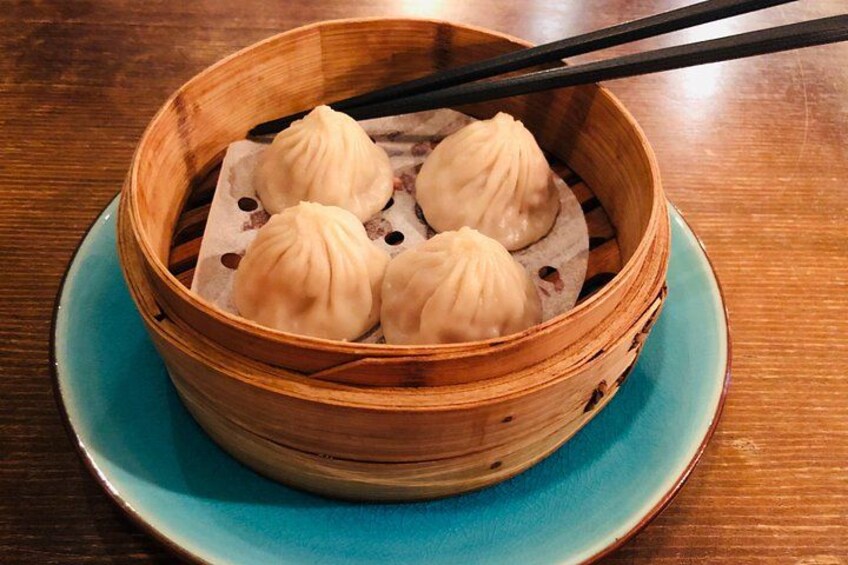 A bamboo steamer with four dumplings on a blue plate. 2