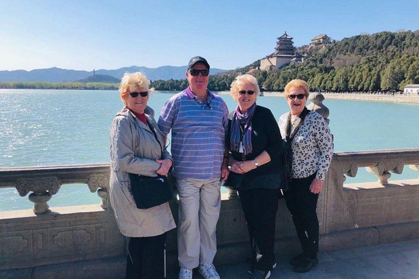 A group of people standing by a body of water with a pagoda in the background. 4