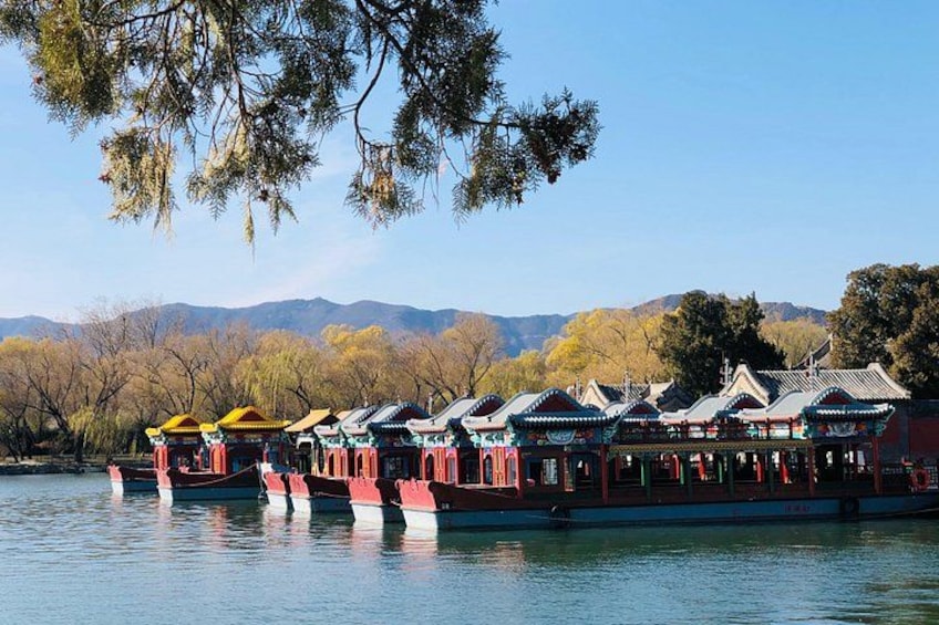 A row of traditional Chinese boats on a calm lake with mountains in the background. 5