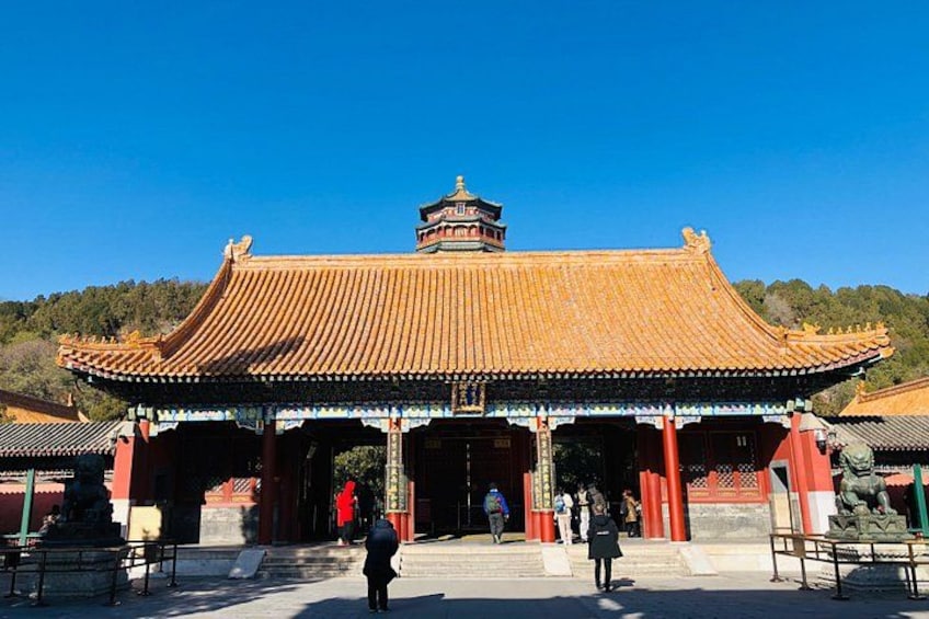 A traditional Chinese gate with a tiled roof, red pillars, and a small tower on top. 2