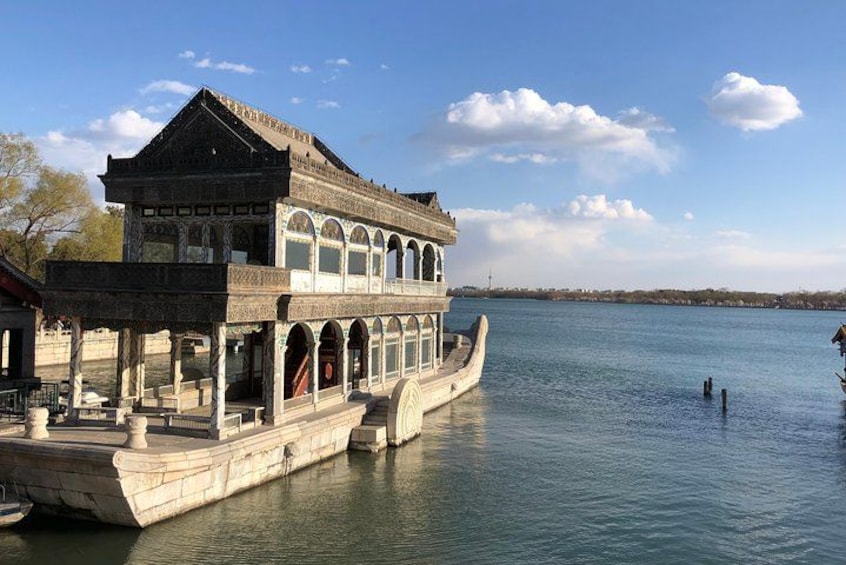 A traditional building with a boat docked in front of it, a calm body of water, and a clear sky. 2