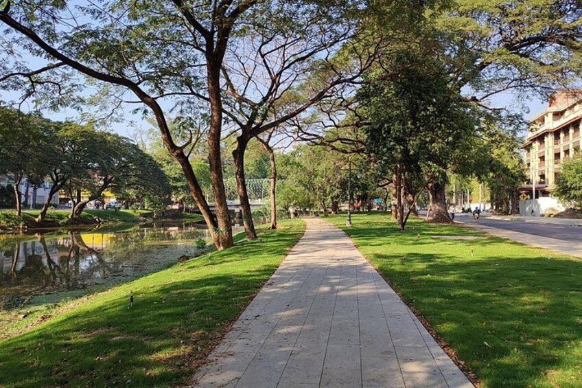 Un parque con un sendero pavimentado, árboles y un cuerpo de agua. 2