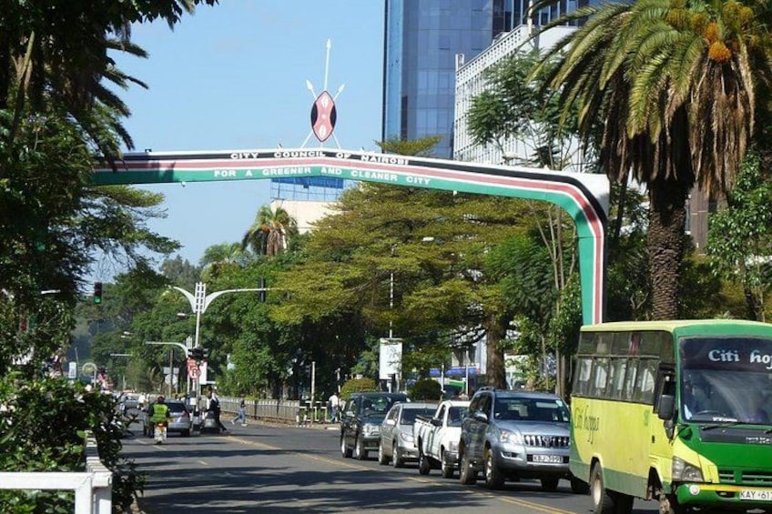 A busy urban street with a green bus, cars, and pedestrians. 1