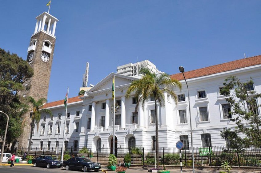 A historic building with a clock tower, palm trees, and a clear blue sky. 2