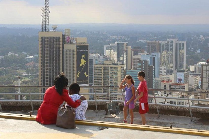 A cityscape with high-rise buildings, a person in a red dress, and two children. 5