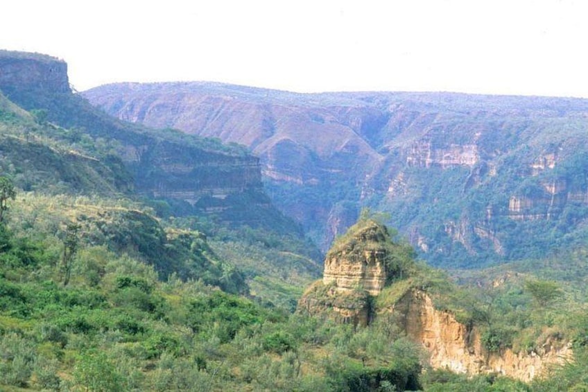 A canyon with a prominent rock formation in the foreground and steep cliffs in the background. 1