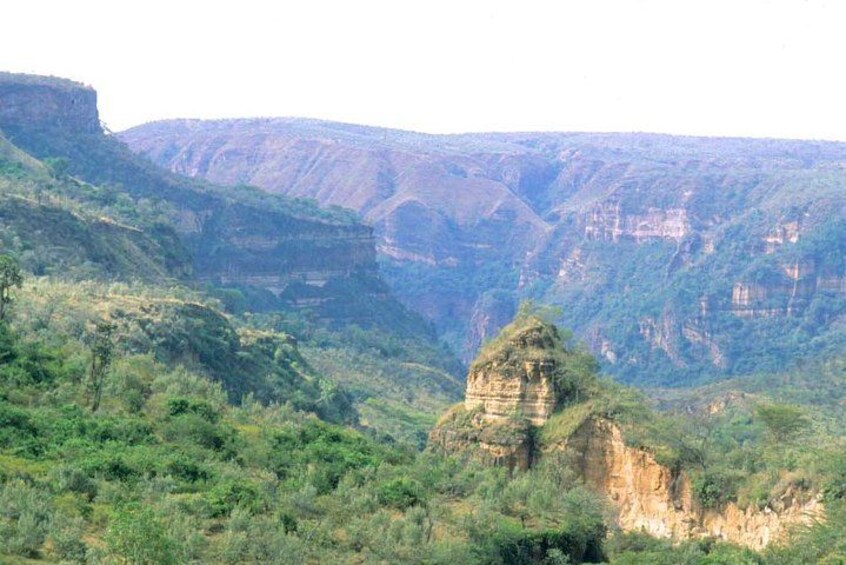 A canyon with a prominent rock formation in the foreground and steep cliffs in the background. 1