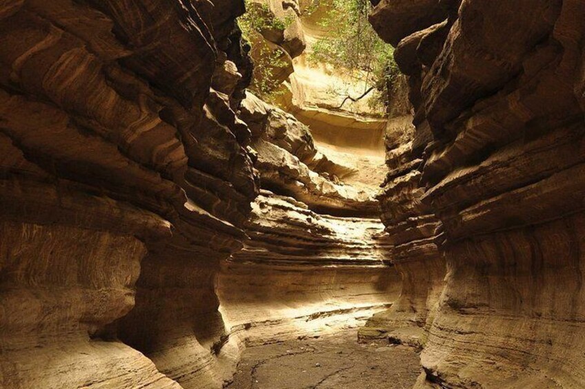 A canyon with layered rock formations and a narrow passageway. 3
