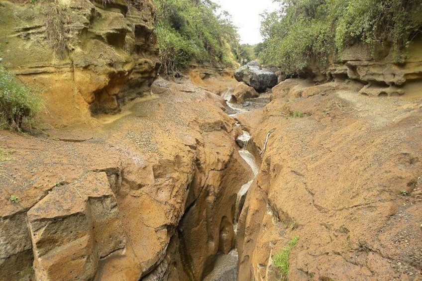 A canyon with a narrow water stream flowing through it. 2