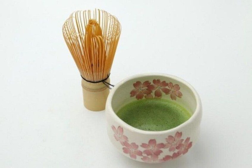 A whisk and a cup with a floral design. 2