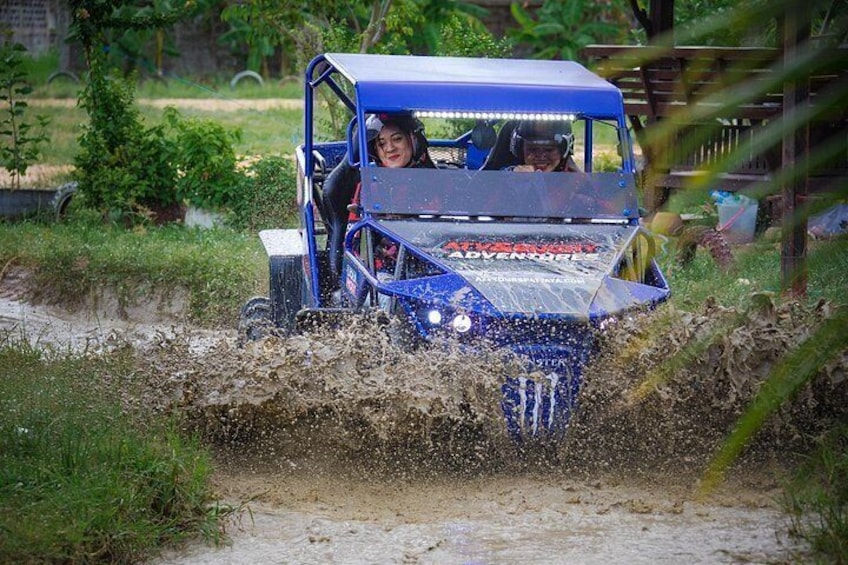 A blue off-road vehicle driving through a muddy path. 4