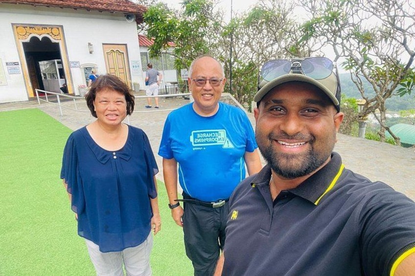 Three people standing in front of a building with a green lawn and a red-tiled roof. 2