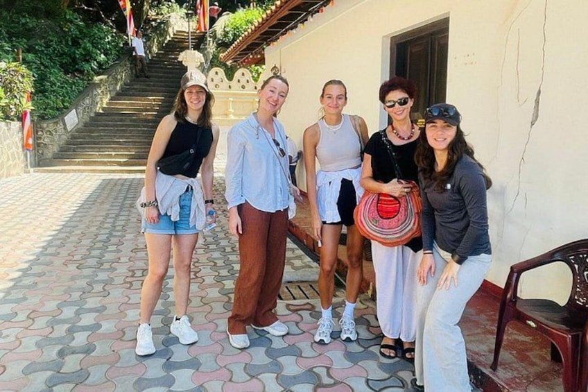 A group of people standing on a patterned pavement, a staircase, and a building with a white wall and a door. 4