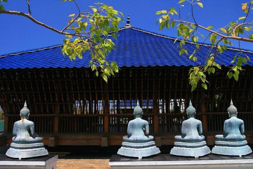 A traditional building with a blue roof, surrounded by a wooden fence, and three stone statues in front. 2