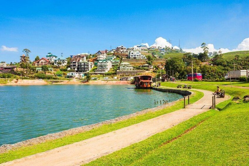A lake with a boat, a pathway, and houses in the background. 5