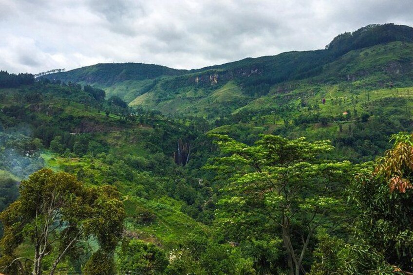 A lush green valley with rolling hills and a prominent rock formation in the center. 2