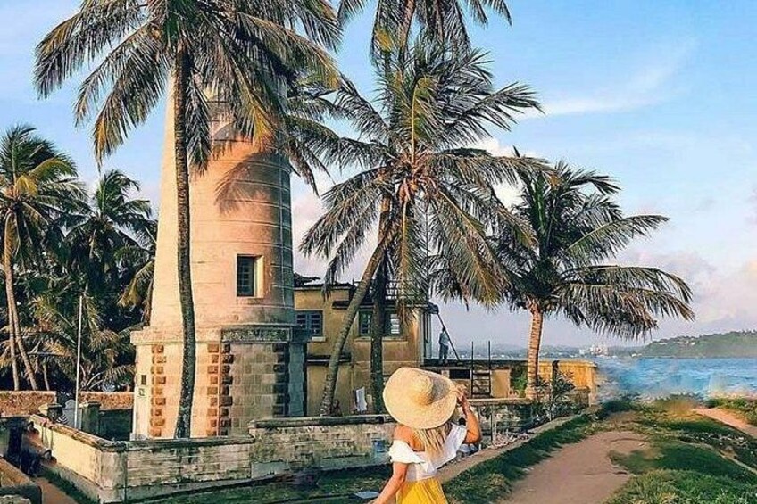A coastal building with palm trees, a pathway, and a view of the sea. 1