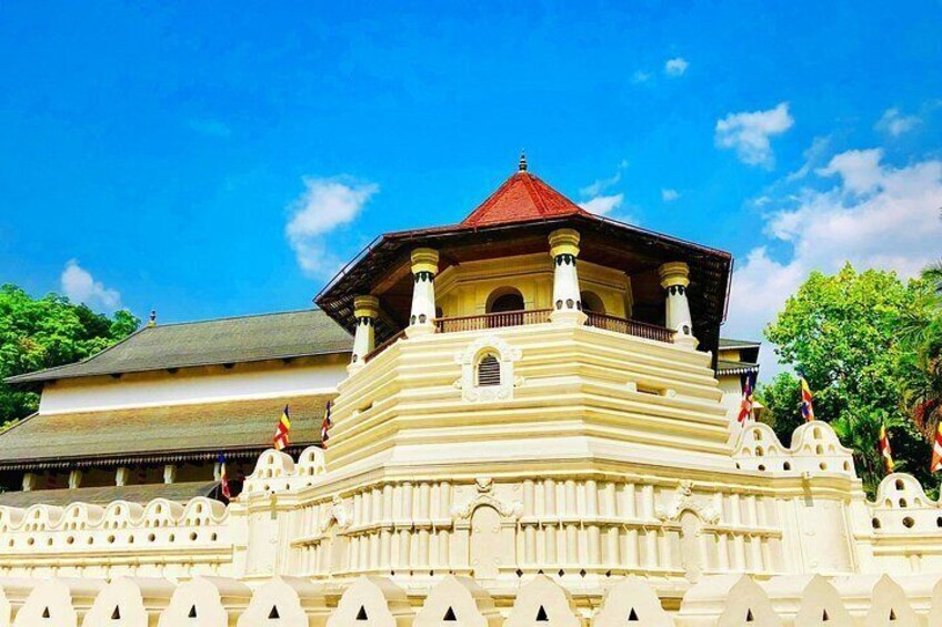 A white, multi-tiered building with a red roof, surrounded by a white wall with decorative elements. 2