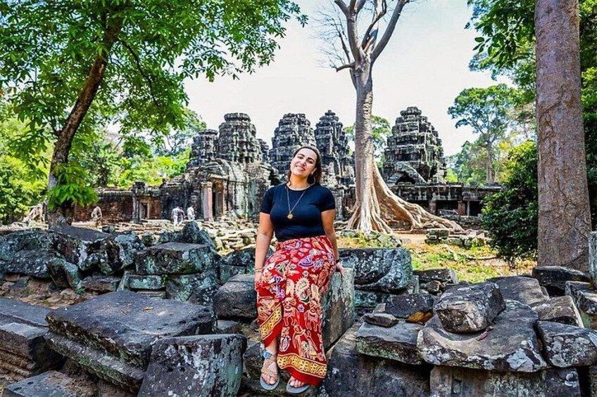 A person sitting on ancient stone ruins with a large tree in the background. 5