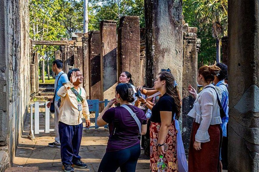 Tourists exploring ancient ruins with stone columns and a white fence. 2