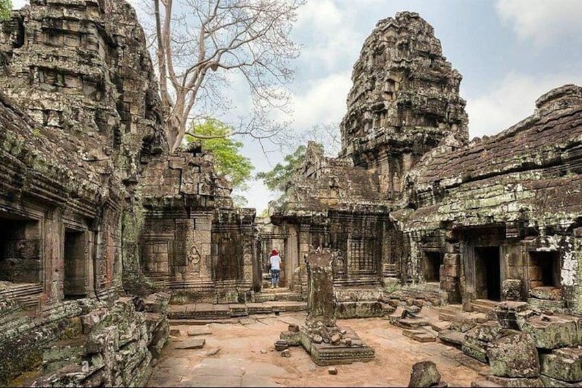 Ancient stone structures with intricate carvings, a central open space, and a person in the background. 4
