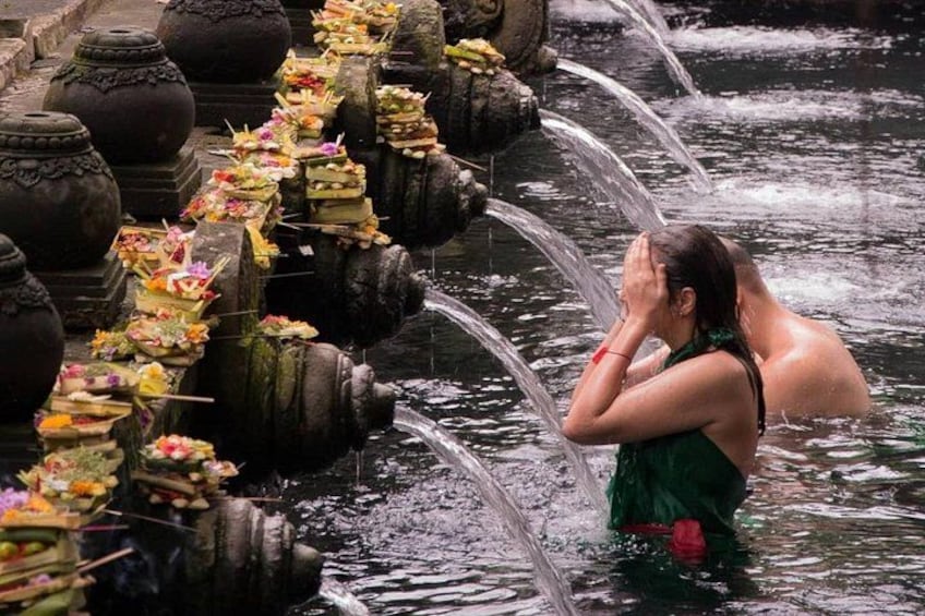 Una persona con un abito verde in una vasca d'acqua con elementi in pietra e decorazioni floreali. 3