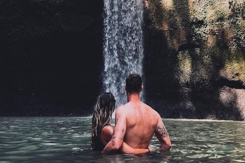 Una coppia seduta in acqua, con una cascata sullo sfondo. 5