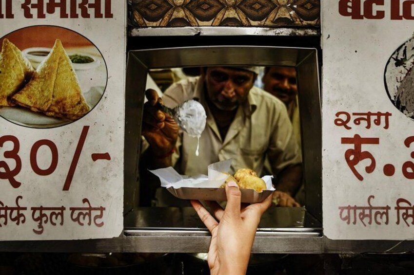 A hand holding a food item near a food stall. 4